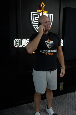 Shawn stands in a podcast studio while talking on a mobile phone.