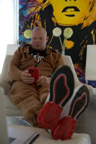 Shawn relaxes in a chair holding a phone in a room.