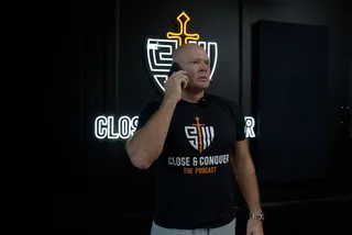 Shawn holds a phone to his ear while standing in a podcast studio.