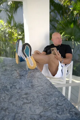 Shawn relaxes in a chair holding a phone outdoors.