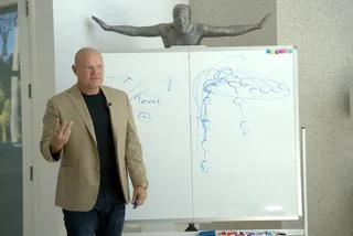 Shawn teaching next to a whiteboard with diagrams in an office.