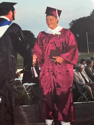 Shawn shakes hands while receiving a diploma during a graduation ceremony.