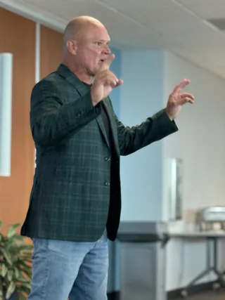 Shawn gestures with his hands while speaking in an office environment.