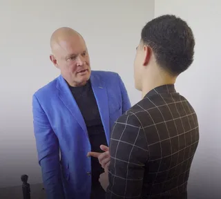 Shawn has a conversation with a colleague in an office.