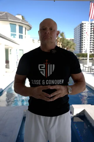 Shawn stands outdoors near a swimming pool in front of a modern home.