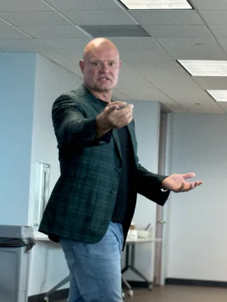Shawn gestures while speaking in an office.