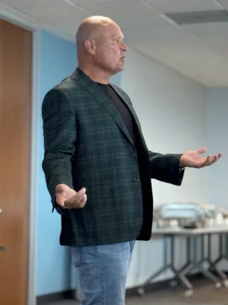 Shawn speaks with hands outstretched in an office.