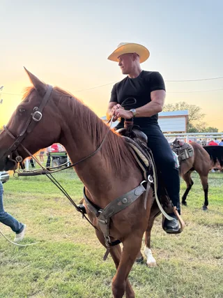 Shawn rides a horse outdoors at a ranch.