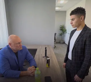 Shawn stands facing a colleague across a counter in an office.
