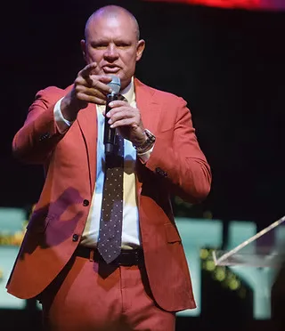Shawn speaks into a microphone on a stage.