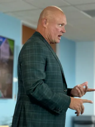 Shawn speaks while gesturing in an office.
