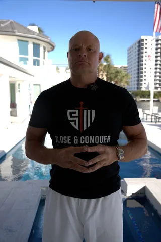 Shawn stands by a swimming pool outdoors.