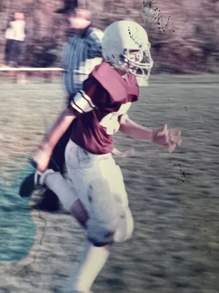 Shawn running on a sports field while wearing a football uniform.