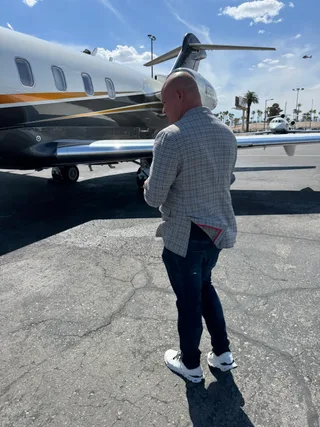 Shawn stands on a tarmac next to a private jet.