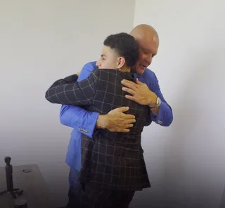 Shawn hugs a colleague in an office.