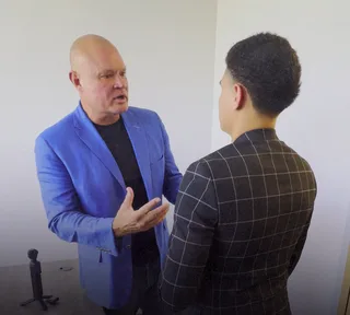 Shawn has a conversation with a colleague in an office.